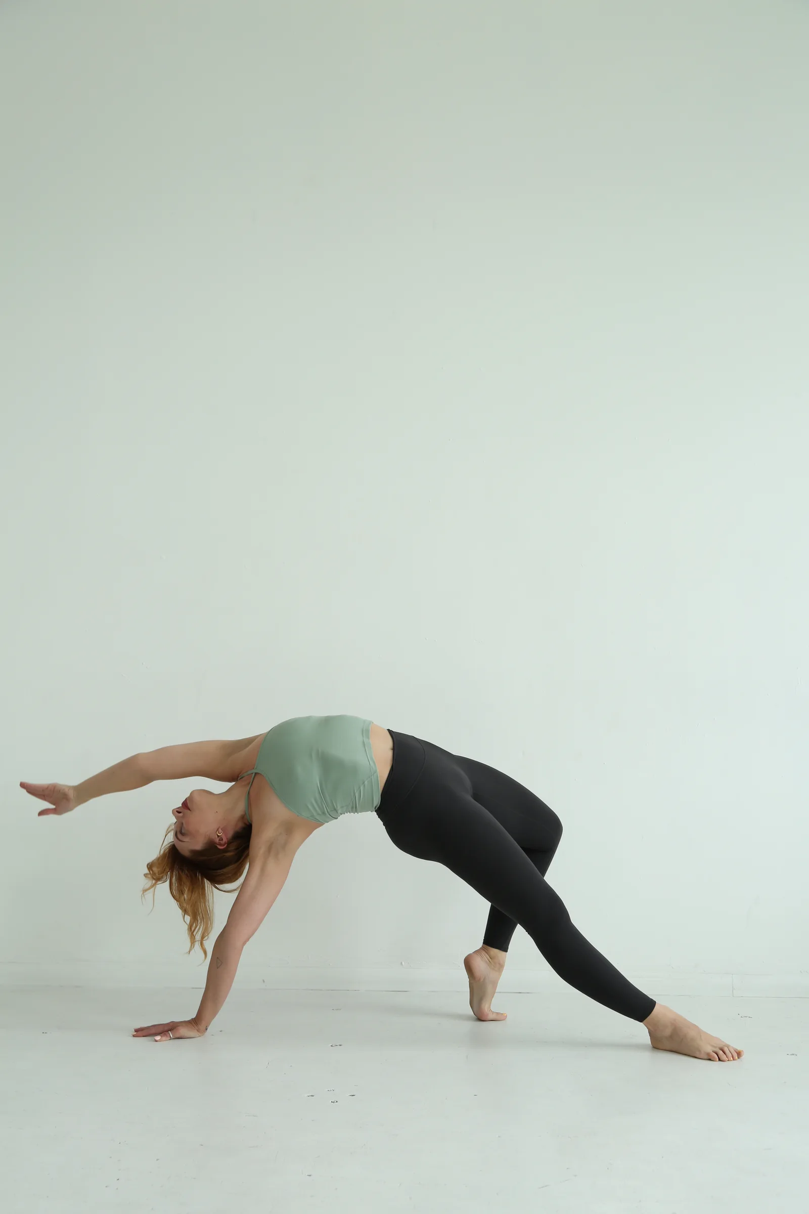 Shannon moving through a sculptural backbend in a pale studio